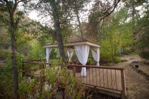 a gazebo with a white curtain on a bridge at Quiet Mind Lodge, Spa & Retreat Sequoias in Kernville
