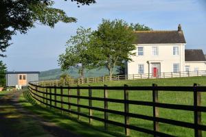 una valla delante de una casa blanca en Glascoed Farmhouse, en Carmarthen
