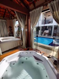 bañera en una habitación con cama y piscina en SPA&Hospedagem Giovannini en Pirenópolis