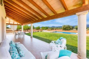 a covered patio with white furniture and a pool at YupiHome Finca Can Soler in Inca