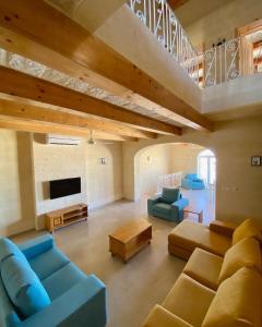 un grand salon avec des canapés bleus et une télévision dans l'établissement Ta' Giga Farmhouse, à Sannat