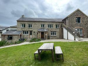 THE OLD RECTORY SOUTHCOTT APARTMENT in Jacobstow 10 mins to Widemouth bay and Crackington Haven,15 mins Bude,20 mins tintagel, 27 mins Port Issac في Jacobstow: منزل حجري امامه طاولة نزهة