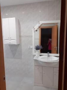een witte badkamer met een wastafel en een spiegel bij Antequera apartamento céntrico in Antequera