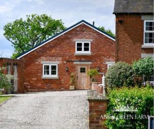 a red brick house with a gravel driveway at Abbey Green Farm in Wem