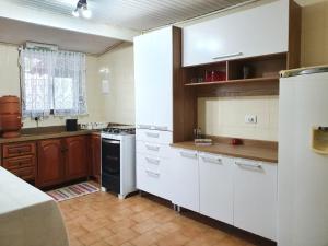a kitchen with white cabinets and a stove top oven at Casa 4 dorms 2 suites - localização perfeita no centrinho e rodeada de natureza in Alto Paraíso de Goiás