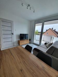 ein Wohnzimmer mit einem großen Holztisch und einem Sofa in der Unterkunft Mierzeja Park 13 apartament 40m2 in Sztutowo
