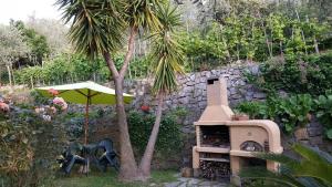 a garden with an umbrella and a grill and a palm tree at L'Uliveto D'Argento in Finale Ligure