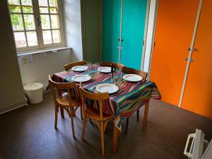 uma mesa de jantar com cadeiras e pratos em Lisons des Sources em Nans-sous-Sainte-Anne