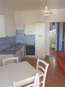 eine Küche mit einem weißen Tisch und Stühlen sowie einem Sofa in der Unterkunft Villetta Terranova 2 in Lampedusa