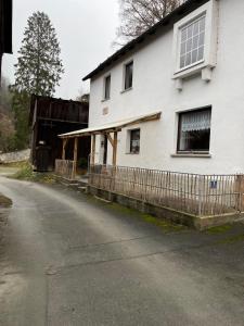 a white house with a fence next to a road at Ferienwohnung Schlossberg 3 in Wirsberg