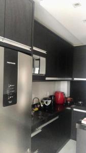 uma cozinha com armários pretos e um frigorífico de aço inoxidável em brisas da maré em Passo de Torres
