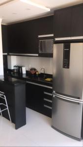eine Küche mit schwarzen Schränken und einem Kühlschrank aus Edelstahl in der Unterkunft brisas da maré in Passo de Torres