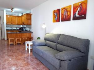 een woonkamer met een bank en een keuken bij Apartamentos Medano - Esmeralda Medano in El Médano