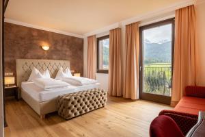 ein Schlafzimmer mit einem Bett und einem großen Fenster in der Unterkunft Historic Hotel Alte Goste in Olang + 213 Fotos