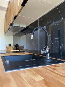 a kitchen with a sink and a black counter top at Apartamenty Osmolice w Stawach in Dęblin