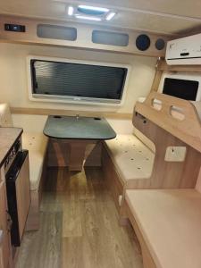 an interior view of an rv with a table and a window at Muscat Caravans in Barka