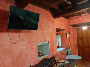 telewizor z płaskim ekranem wiszący na czerwonej ścianie w obiekcie Casa Piccolo Borgo w mieście Campello sul Clitunno