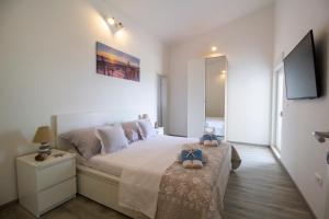a white bedroom with a large bed and a flat screen tv at Apartman Cicibella in Kaštela