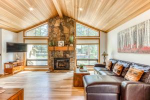 a living room with a stone fireplace and leather couches at Sundial on Deck in Sunriver