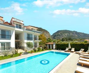 a villa with a swimming pool and mountains in the background at Kerem Apart Hotel in Göcek