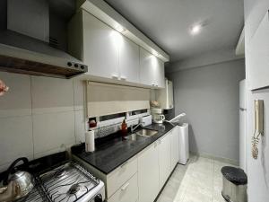 a kitchen with white cabinets and a sink and a stove at Premium loft dúplex con terraza in Cordoba