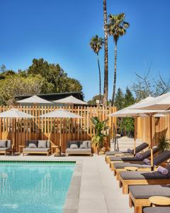 a pool with chaise lounge chairs and umbrellas at Hotel June Malibu in Malibu