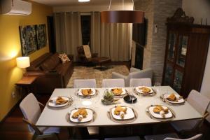 una mesa con platos de comida en la sala de estar en DUPLEX COM JACUZZI NA BORGES - SATTVA HOME, en Gramado