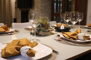 una mesa con copas de vino, platos y servilletas en DUPLEX COM JACUZZI NA BORGES - SATTVA HOME, en Gramado