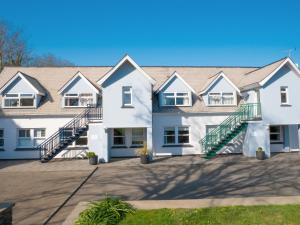 Un grand bâtiment blanc avec des escaliers se trouve juste devant. dans l'établissement Ellingham Apartments, Bordeaux Harbour, Guernsey, à Vale