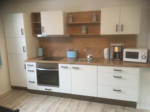 a kitchen with white cabinets and a sink and a microwave at Ferienwohnung Schlossberg 2 in Wirsberg