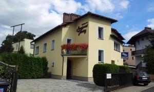 a yellow building with a balcony with red flowers at Pensjonat U Janiny Bolesławiec in Bolesławiec