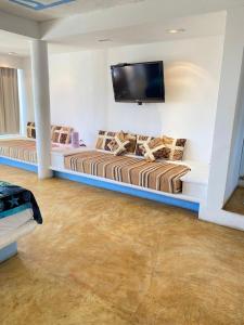 a living room with two beds and a flat screen tv at Casa de las Olas Surf & Beach Club in Acapulco