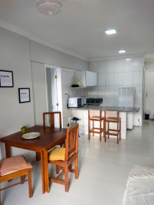 a kitchen with a wooden table and chairs in it at Farol Barra Flat in Salvador