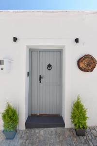 a white front door of a house with two potted plants at Tramuntana in Ano Syros