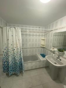 a bathroom with a tub and a sink and a shower curtain at Apartamento Arena y Sal in Torrox Costa