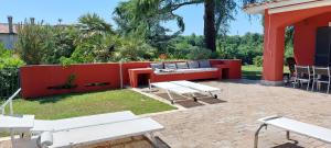 a patio with white benches and a red fence at IL CICLAMINO POOL FOR YOUR SOLE USE BIG IN-GROUND - 70m2 house & 300m2 outdoor, child & pet friendly, 10 minutes drive to Montebello Station connecting to Rome centre in 20 minutes, 3 minutes drive to supermarket -4 language warm guest care in Riano