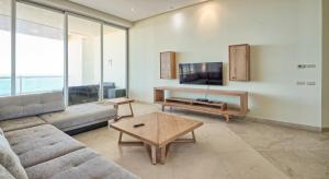 a living room with a couch and a tv at Luna Blanca Penthouse by Kivoya in Puerto Peñasco