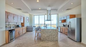 a kitchen with stainless steel appliances and a living room at Luna Blanca Penthouse by Kivoya in Puerto Peñasco