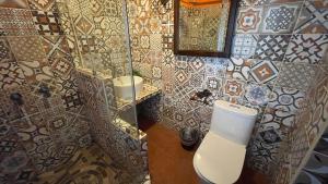 a bathroom with a toilet and a tiled wall at Hotel Vista San Francisco in Antigua Guatemala