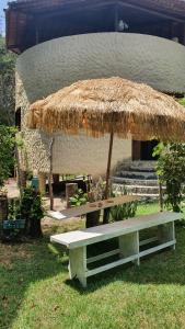 una mesa de picnic con un paraguas de paja y un banco en Apartamentos GoPipa934, en Pipa