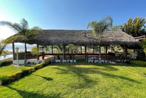 einen Pavillon mit Stühlen und einem Grasdach in der Unterkunft Jardín Quinta Las Fuentes Cabañas, Valsequillo. PUEBLA in Puebla