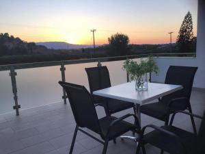 a table and chairs on a balcony with the sunset at Zante Melina's Apartment in Argassi