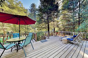 een houten terras met een tafel en stoelen en een parasol bij Cazadero Escape in Cazadero