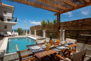 un patio con una mesa y una piscina en Villa Elizabeth - Seafront Classic Villa! en Zakynthos