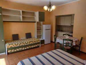 Cet appartement comprend une chambre avec deux lits, une table et une cuisine. dans l'établissement Residenza Il Poggio, à San Bartolomeo al Mare