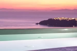 a view of the ocean with a sunset in the background at Elia Cave Suites in Imerovigli
