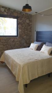 a bedroom with a large bed with a stone wall at Casa de Piedra in Zonda