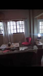 ein Wohnzimmer mit einem roten Stuhl und Fenstern in der Unterkunft los agapantus in Ingeniero Maschwitz