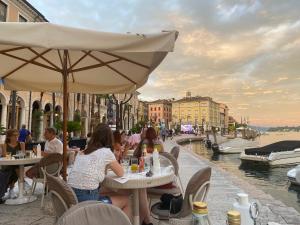a group of people sitting at tables near a canal at Violetta Maison Salò in Salò