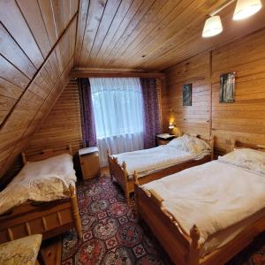 a room with three beds in a wooden cabin at Dom Nad Jeziorem Staw in Gawrych Ruda